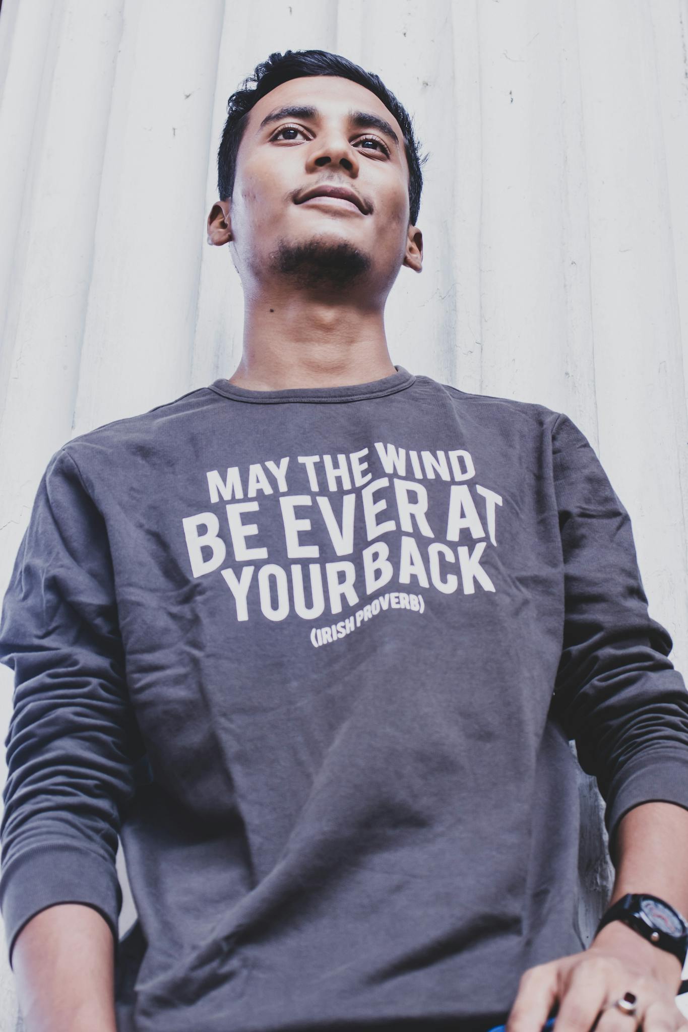 Portrait of a young man in a casual outfit with a motivational quote on his shirt.